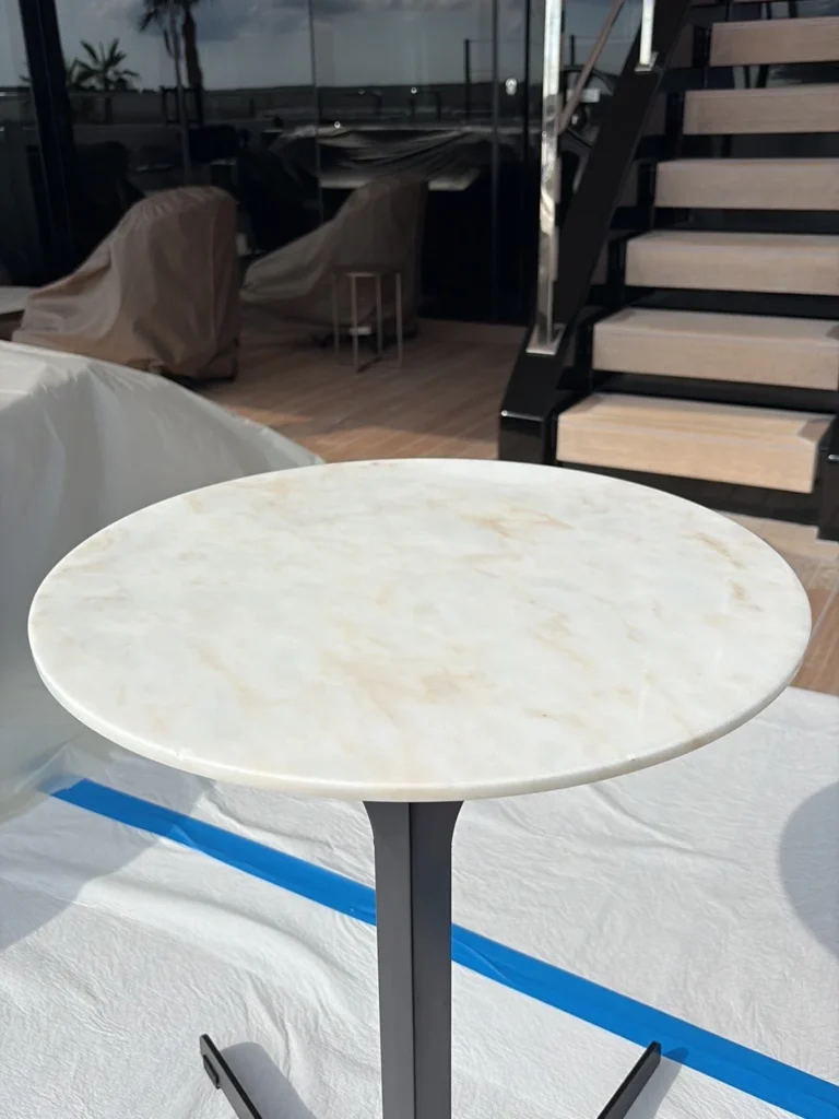 Round marble table on a yacht deck after polishing, protection tape visible